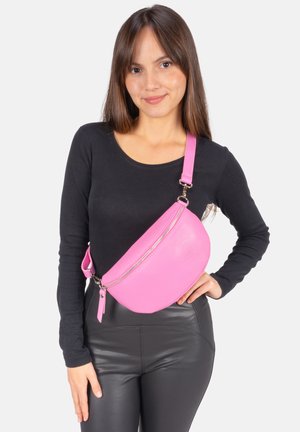 Sac besace en cuir rose avec une finition texturée, forme courbée, fermeture éclair et bandoulière ajustable, porté à l'épaule.