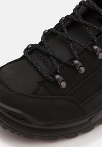 Schwarzer Wanderschuh mit glattem Obermaterial, strukturierten Schnürsenkeln und runden Metallösen. Verfügt über eine robuste, profilierte Sohle für Stabilität.