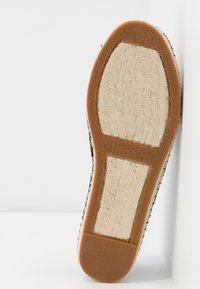 Semelle d'une chaussure taille 6 ½ avec des fibres beiges texturées et des sections en caoutchouc marron, marquée "Made in China" visible sur fond blanc.