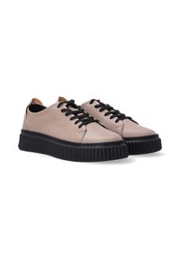Lichtbeige leren sneakers met zwarte veters, dikke zwarte profielzool, ronde neus en contrasterende tan hieltab. Gladde textuur.