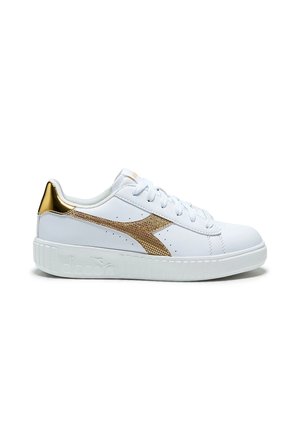 Sneaker bianca low-top con logo laterale dorato testurizzato e dettaglio sul tallone, lacci bianchi e suola bianca spessa.