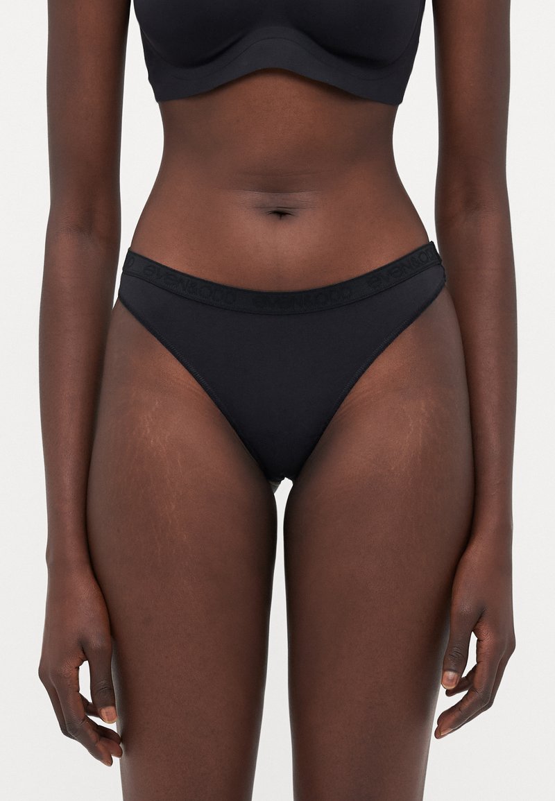 Bas de bikini noir en tissu doux, avec une ceinture confortable embossée du nom de la marque. Design taille basse avec une couverture modérée.
