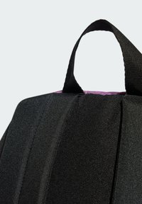 Zaino nero con un tessuto testurizzato, dotato di manico superiore e interno viola. Il design include pieghe per una maggiore struttura.