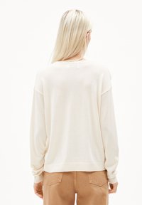 Light beige sweater with a relaxed fit, long sleeves, and ribbed hem. Soft texture with minimal detailing. Back view showing simplicity.