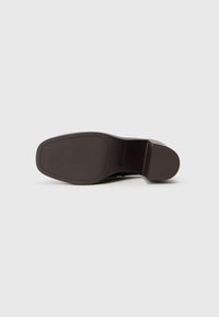 Talpă de pantof din cauciuc maro cu o suprafață texturată, cu model; călcâi ușor ridicat; margini netede cu un design al vârfului rotunjit.