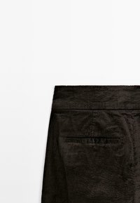 Czarne spodnie z korduroyu z pionowymi prążkami, z elastycznym pasem i tylną kieszenią. Gładka tekstura i minimalistyczny design.