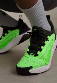 Scarpe da atletica verde neon con tomaia testurizzata, dettagli neri e suole bianche. Le caratteristiche includono lacci, logo e sovrapposizioni a motivo.