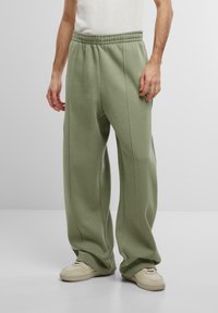 Pantalons de survêtement verts clair, surdimensionnés, avec une taille élastique froncée, des jambes droites et des coutures latérales pour la structure. Matière en coton douce.
