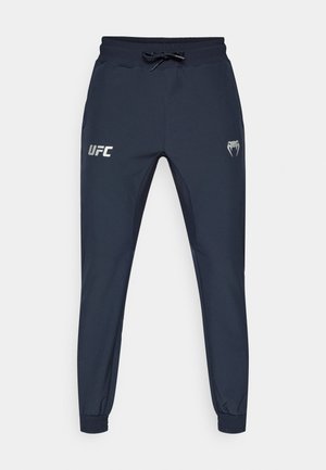 Tumesinised treeningpüksid valmistatud kerge kangaga, millel on elastne vöökoht paelaga, tihedad mansetid ja vasakul reiel hõbedane UFC logo.