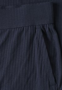 Tissu côtelé bleu foncé montrant un gros plan d'une ceinture et de l'ouverture d'une poche sur un vêtement.