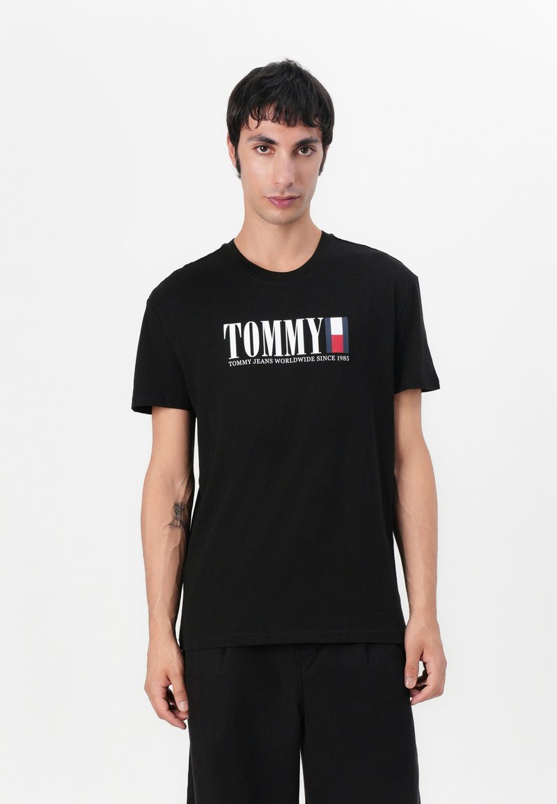 Svart bomulls T-skjorte med "TOMMY" logo i hvitt og rødt, rund hals, kort ermer, glatt tekstur og avslappet passform.