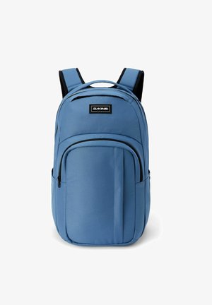 Zaino Dakine blu con spallacci imbottiti, tasca frontale con cerniera e maniglia superiore su sfondo bianco.