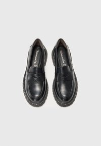 Melnas ādas kurpes ar gludu apdari. Apaļa purngalu forma un dekoratīva lente uz priekšpuses. Bieza zole ar redzamām šuvēm.