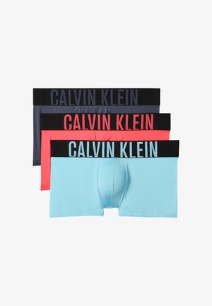 Trois paires de boxers Calvin Klein en bleu, corail et gris foncé, chacune avec une ceinture noire et un lettrage de la marque en caractères gras.