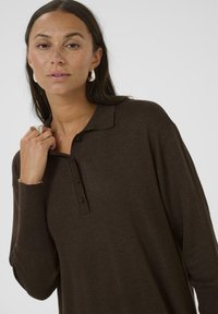 Polo en tricot marron à manches longues avec une patte de boutonnage et un col. Texture lisse, coupe décontractée et poignets côtelés.