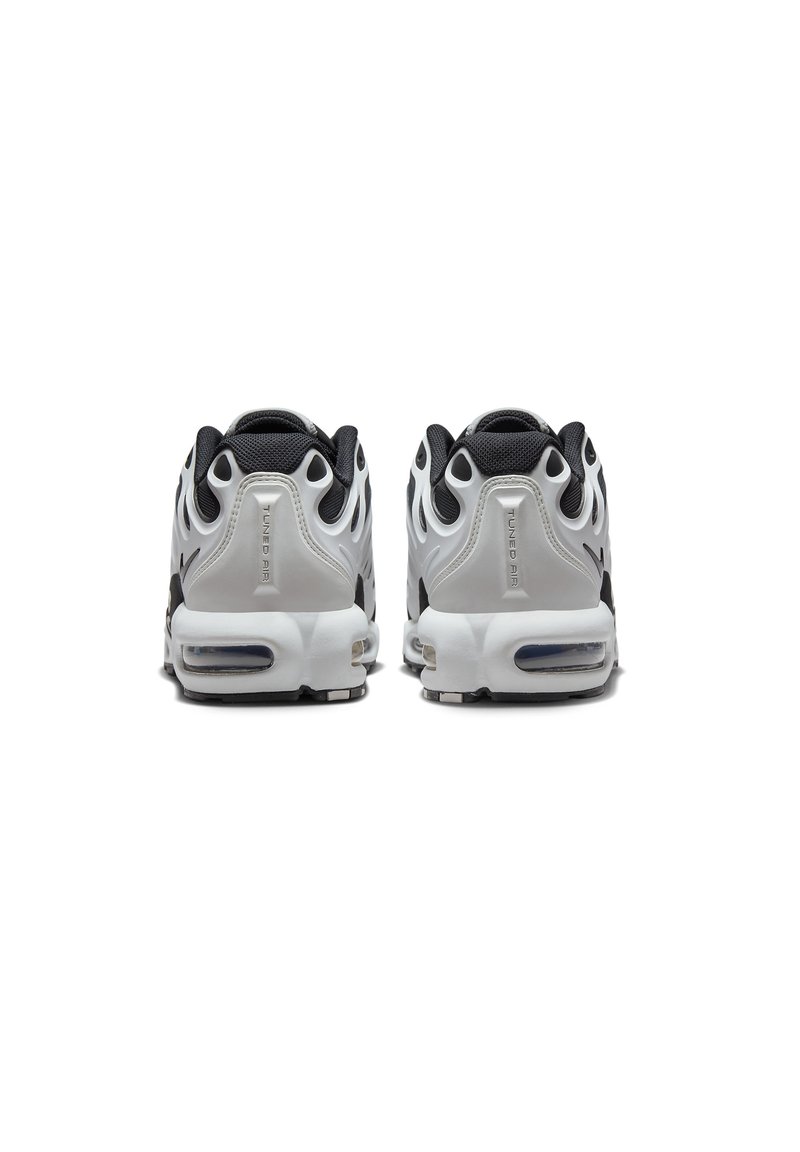 Baskets de sport noir et blanc avec des matériaux en mesh et synthétiques, amorti d'air visible, forme de talon arrondie et accents texturés.