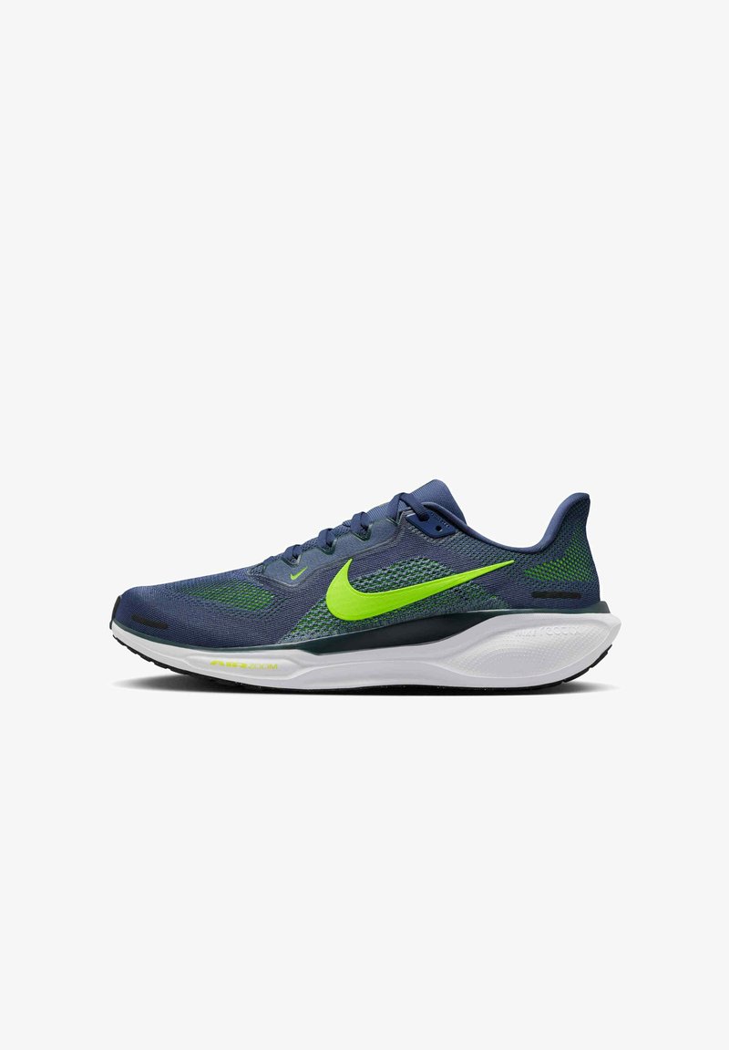 Scarpa da corsa blu navy e verde con un brillante baffo Nike verde, suola bianca imbottita e suola nera.