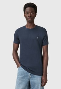Námorně modré bavlněné tričko s krátkým rukávem, kulatým výstřihem a malým logem na hrudi. Jednoduchá, hladká textura. Volný střih.