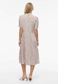 Sukienka midi w kwiatowy wzór z krótkimi rękawami, dekoltem w serek, talią podkreśloną wstążką i falbanistym dołem. Materiał ozdobiony małymi czerwonymi, niebieskimi i zielonymi kwiatami na jasnym tle.