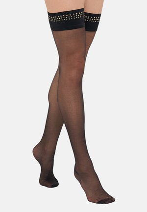 Calze nere fino alla coscia con una texture trasparente, caratterizzate da un bordo solido in cima decorato con borchie dorate. Design con punta aperta.