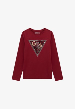 Langärmliges burgunderfarbenes T-Shirt mit einem dreieckigen Grafikdesign, das das Wort "GUESS" in roten, goldenen und schwarzen Texturen zeigt, verziert mit Pailletten und Schriftakzenten.