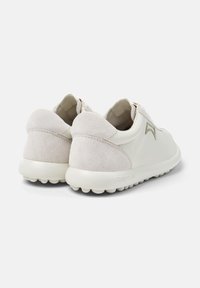 White sneakers made of leather and suede, featuring a textured back, rounded toe, and a flexible rubber sole with small traction dots.