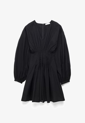 Musta pitkähihainen mekko, jossa syvä V-pääntie, joustava vyötärö, rypytetyt hihansuut, liehukehelma ja takana oleva vetoketjukiinnitys.