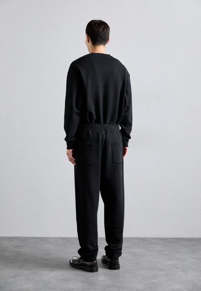 Svart sweatshirt och matchande joggers gjorda av mjukt tyg. Sweatshirten har lång ärm och joggersen har elastisk midja samt bakfickor.