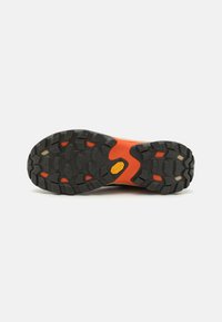 Czarny i pomarańczowy bieżnik butów trekkingowych z wytrzymałym wzorem bieżnika. Logo Vibram na pięcie, wykonane z trwałego gumowego materiału i o teksturowanym uchwycie.