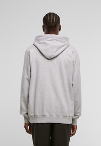 Grå hettegenser laget av mykt stoff. Har lange ermer og en avslappet passform. Minimalistisk design uten synlige mønstre.