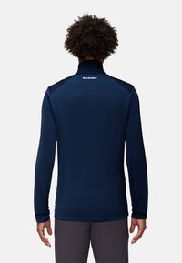 Mörkblå långärmad tröja med hög krage, med en logotyp på baksidan. Tillverkad av ett slätt material har den en figurnära design och diskreta sömmar.