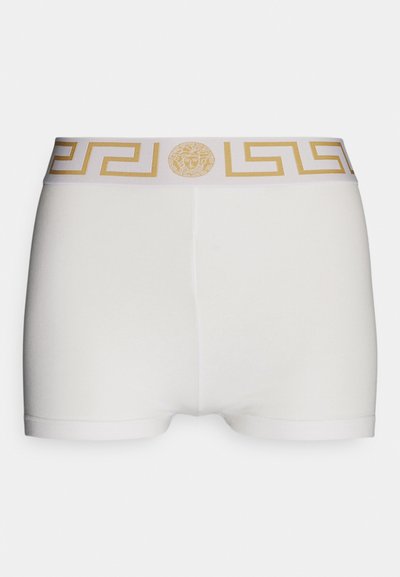 Baltos medvilniniai trumpikės su plačiu auksiniu ir baltu graikų rakto raštu ant juosmens, kuriame pavaizduota centrinė Medūzos simbolika.