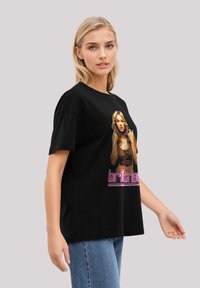 Black cotton t-shirt featuring a printed portrait and text of a female figure, with short sleeves and a relaxed fit, worn with blue jeans.