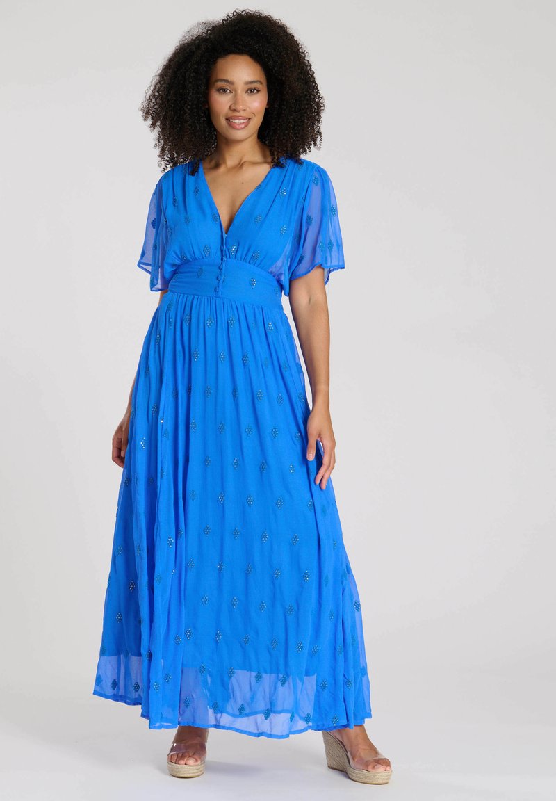 Blå maxiklänning med korta, flödande ärmar, en V-hals och utsmyckningar. Klänningen har en figursydd midja och en lös, flödande kjol.