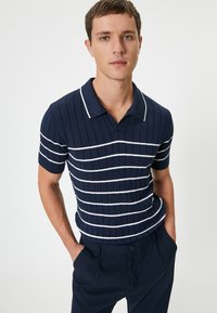Polo de manga corta en color navy con textura acanalada y rayas horizontales blancas. Cuenta con un cuello clásico y un diseño ajustado.