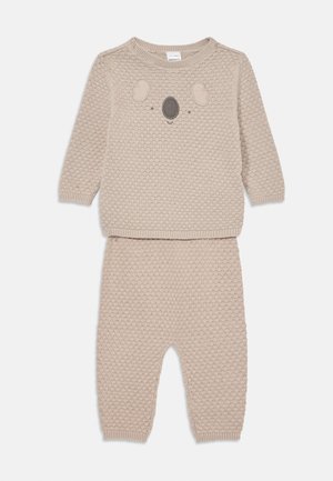Beige neulepuku vauvoille, joka koostuu pitkähihkaisesta paidasta, jossa on koala-kasvokuvio, ja vastaavista teksturoiduista housuista.