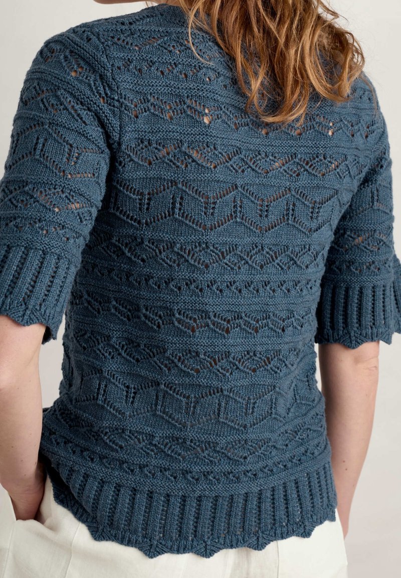 Pull en tricot bleu avec manches courtes volantées. Présente des motifs ajourés complexes, un ourlet côtelé texturé et un matériau doux et léger.