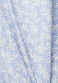 Il tessuto floreale blu presenta piccoli fiori bianchi e giallo chiaro disposti lungo sottili rametti, con una texture liscia e un aspetto leggero.