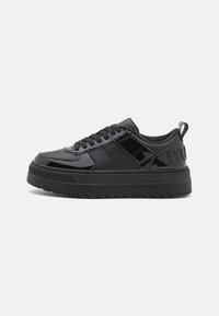 Schwarze Sneaker mit einer Kombination aus glänzenden und matten Materialien, runder Zehenpartie, strukturiertem Sohlenprofil und Fersenlasche mit geprägt Logo-Detail.