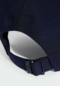 Námořnická modrá čepice s texturovanou tkaninou, zakřiveným kšiltem a nastavitelným páskem se plastovou sponou. Viditelný detail prošívání.