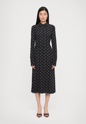 Long-sleeve, collared dress in navy with white swirl patterns. Fitted waist with a belt, flowing skirt, and button cuffs. Smooth fabric texture.