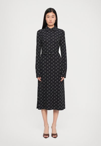 Langärmliges, kragenloses Kleid in Marineblau mit weißen Wirbelmustern. Taillierter Schnitt mit einem Gürtel, fließendem Rock und Knopfmanschetten. Glatte Stoffstruktur.