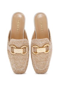 Zapatos de punto en beige tipo slip-on que presentan una forma cuadrada estructurada, un acento decorativo de hardware dorado y un interior suave en tono marrón.