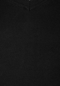 Svart stickad tröja med V-halsdesign. Tyget verkar mjukt och texturerat med en jämn ribbad struktur.