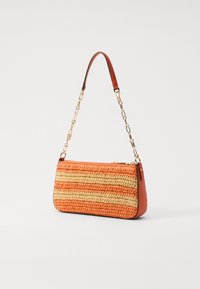 Pochette tissée en fil orange et beige avec un côté en cuir lisse orange, dotée d'une poignée en chaîne dorée et d'une fermeture zippée.