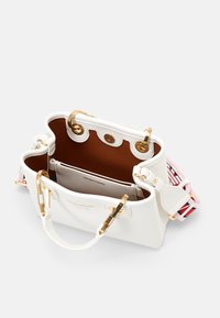 Borsa in pelle bianca con dettagli in oro, foderatura interna marrone e una tracolla a fantasia. Presenta bordi arrotondati e un design con apertura superiore.