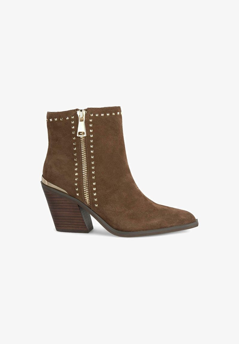 Brązowe zamszowe botki za kostkę z ostrym noskiem, z złotym zamkiem błyskawicznym i ćwiekowanymi zdobieniami po bokach. Słupkowy obcas z teksturą imitującą drewno.