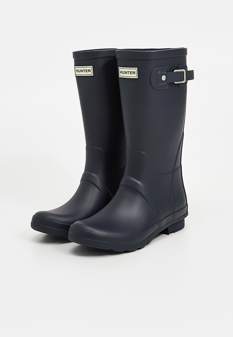 Botas de lluvia de goma azul marino con una textura suave, punta redondeada y detalle de hebilla lateral. Presentan suelas planas para mayor estabilidad.
