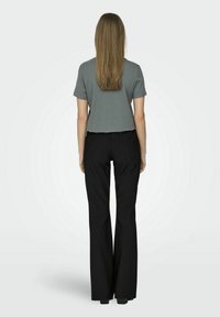Top grigio a maniche corte abbinato a pantaloni neri a zampa d'elefante, che mette in risalto un design semplice e un tessuto liscio. L'outfit appare casual e strutturato.