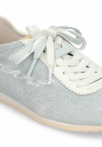 Baskets en daim bleu clair avec bordure blanche en zigzag, lacets superposés noués en nœud, et semelle beige.